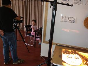 小女孩正在為沙畫(huà)廣告片配音